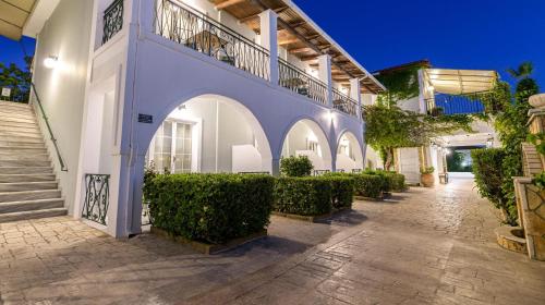 a courtyard of a house with white walls and bushes at Sofia's Hotel in Kalamaki