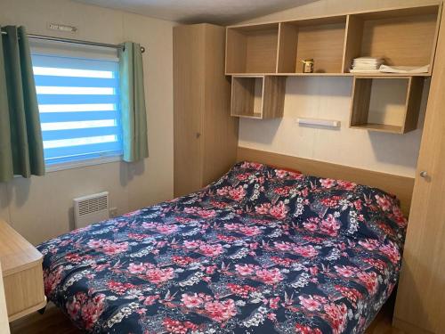 - une petite chambre avec un lit et une couverture fleurie dans l'établissement Mobil Home, à Clohars-Carnoët