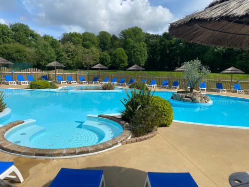 - une grande piscine avec des chaises bleues dans un complexe dans l'établissement Mobil Home, à Clohars-Carnoët