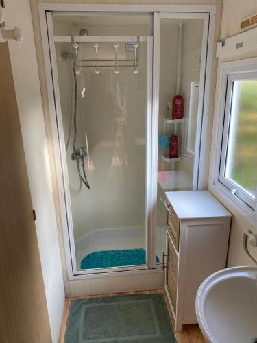 une salle de bain avec douche et lavabo dans l'établissement Mobil Home, à Clohars-Carnoët