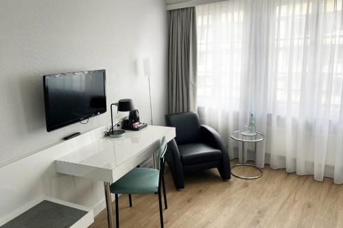a hotel room with a desk with a television and a chair at Garner Hotel Berlin - Checkpoint Charlie by IHG in Berlin