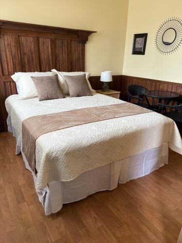 a bedroom with a large bed with a wooden headboard at Hôtel Sous la Croix 152725 in Tadoussac