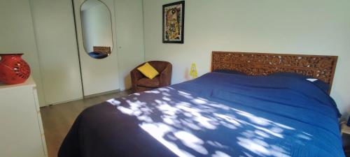 - une chambre avec un lit bleu et une chaise dans l'établissement Vivre le Bassin !, à La Teste-de-Buch