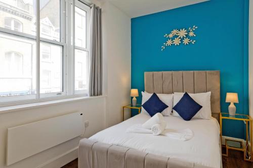 a bedroom with a large bed with a blue wall at Imperial Middlesex Street Apartments in London