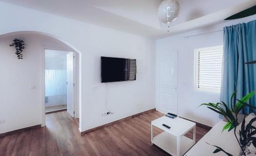 a white living room with a tv on the wall at Casa Min26 in Caleta De Fuste