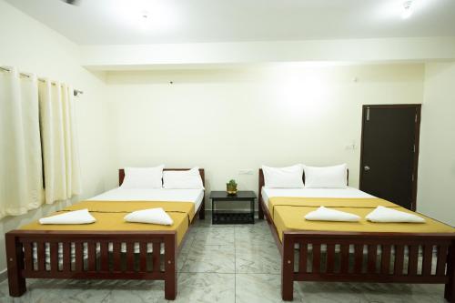 two beds in a room with two tables at Golden Crest Residences in Napoklu