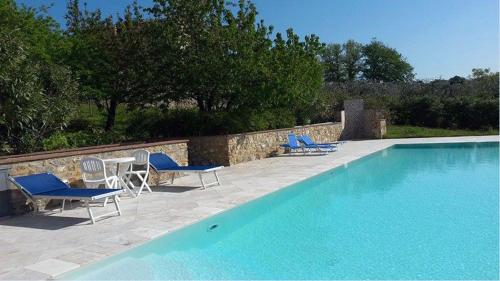 a swimming pool with blue chairs and a table and chairs at Relais Villa Sensano in Pignano