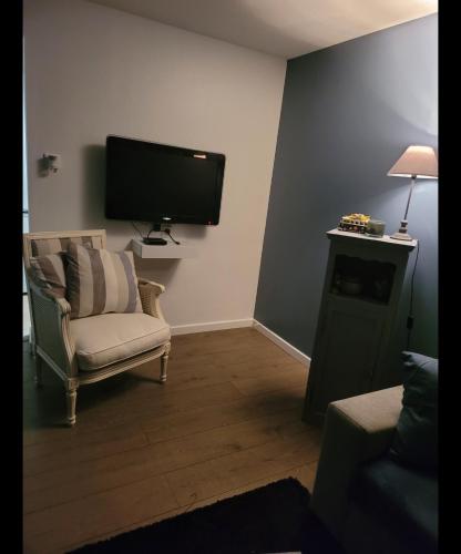 a living room with a chair and a flat screen tv at Appartement cosy proche de la plage in Brétignolles-sur-Mer