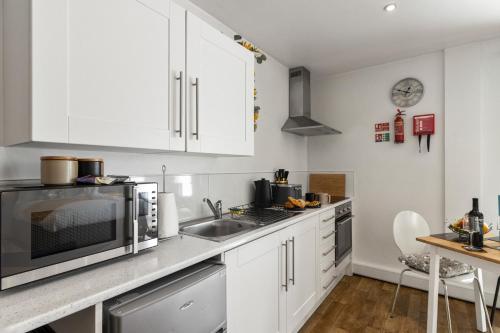 a kitchen with white cabinets and a sink at City Centre Studio Apartments - Ashton Apartment - Short Stays UK Ltd in Exeter