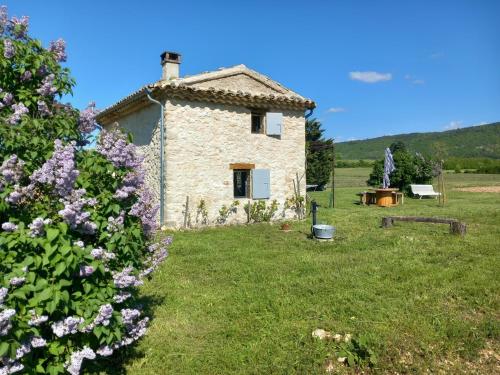 a stone house in a field with purple flowers at Le grangeon des Hermas in Sault-de-Vaucluse