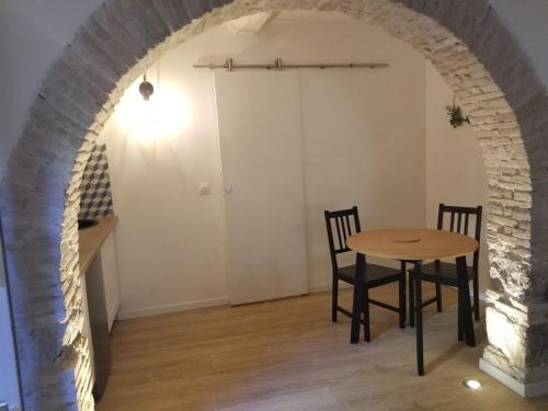 une table et des chaises dans une pièce avec une arche dans l'établissement Studio de charme dans un ancien moulin à huile d'olive, à Cagnes-sur-Mer