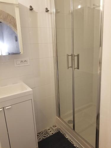 une douche avec une porte vitrée dans une salle de bain dans l'établissement Studio de charme dans un ancien moulin à huile d'olive, à Cagnes-sur-Mer