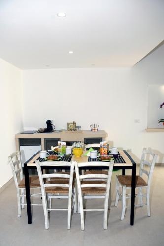 a dining room table with chairs and a kitchen at Miria B&B in Castrignano del Capo
