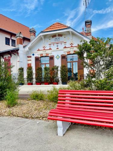 a red bench sitting in front of a building at Villa Salve Maria, proche plage et centre ville, ménage et draps compris in Arcachon