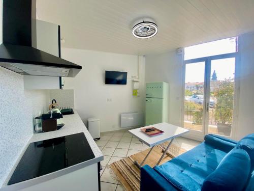 a living room with a blue couch and a kitchen at Villa Salve Maria, proche plage et centre ville, ménage et draps compris in Arcachon