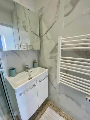 a white bathroom with a sink and a mirror at Villa Salve Maria, proche plage et centre ville, ménage et draps compris in Arcachon