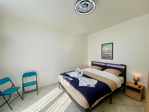 a bedroom with a bed with two chairs and a clock at Villa Salve Maria, proche plage et centre ville, ménage et draps compris in Arcachon