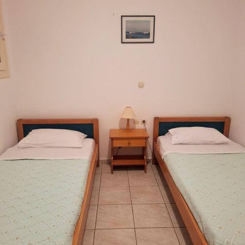 two twin beds in a room with a night stand at Athos Studios in Tinos Town