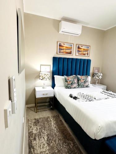 a bedroom with a large bed with a blue headboard at PrimVilla Apartment in Gaborone