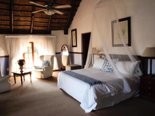 a bedroom with a bed with a mosquito net at Monchique Boutique Guest House in Muldersdrift