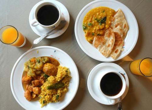 a table with two plates of food and two cups of coffee at Hotel Holiday Park International Limited Cumilla in Comilla
