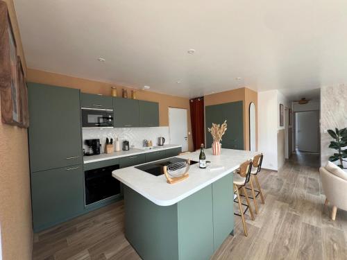 une cuisine avec des placards verts et un comptoir blanc dans l'établissement l Orbinicaise, à Trémuson