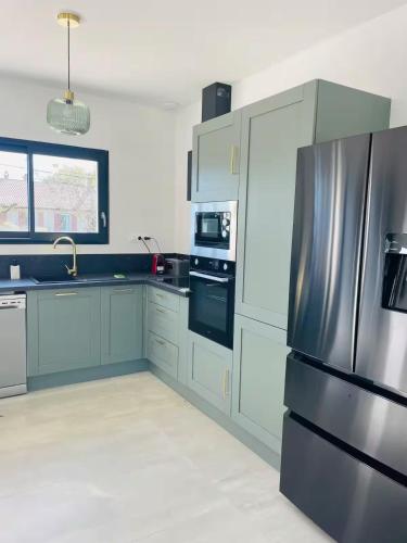a kitchen with a stainless steel refrigerator and white cabinets at Maison moderne avec Piscine in Creysse