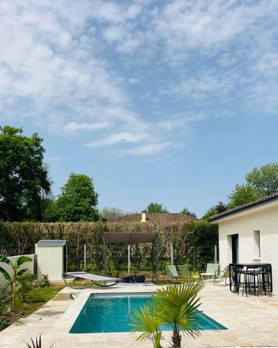 a swimming pool in a backyard with a table and chairs at Maison moderne avec Piscine in Creysse