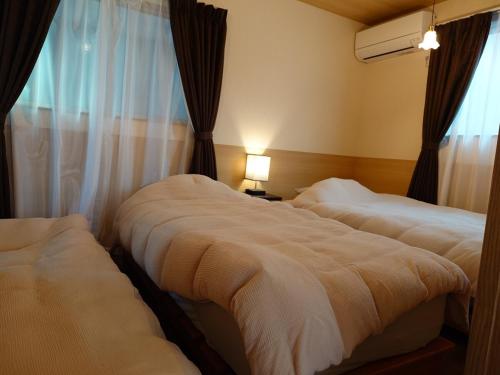 two beds in a hotel room with a window at Somnus豊田 ペットOK 最大宿泊人数12名!1棟貸切の宿 in Toyota