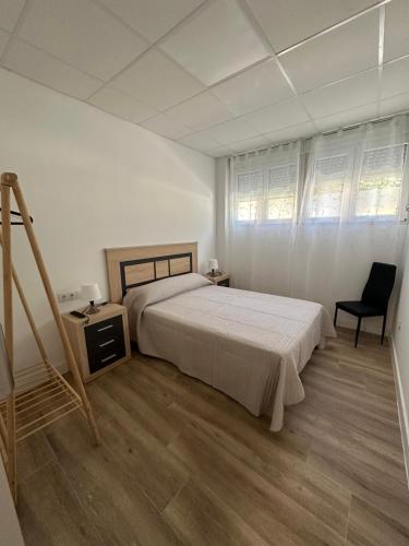 a white bedroom with a bed and a chair at Apartamento tipo loft valencia in Paiporta