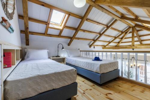 two beds in a room with wooden floors at Blue Heaven Loft House in Skopelos Town
