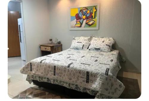 a bedroom with a bed and a painting on the wall at Cantinho do Aconchego in Campo Grande