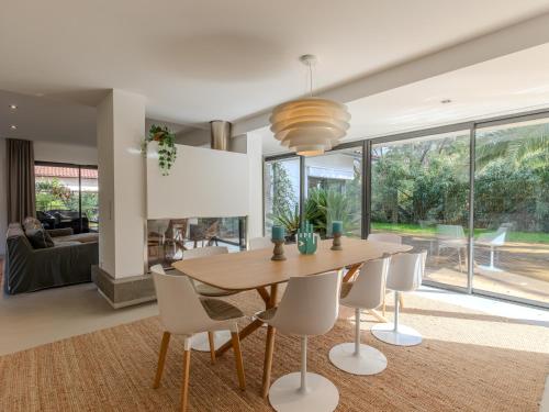 une salle à manger avec une table en bois et des chaises blanches dans l'établissement Villa Hossegor, à Hossegor