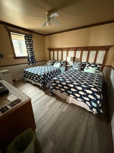 a bedroom with two beds and a ceiling fan at Hôtel Sous la Croix 152725 in Tadoussac