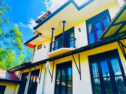 a yellow and white house with a balcony and windows at Greenmoret AgriTourism Villa in Bandarawela