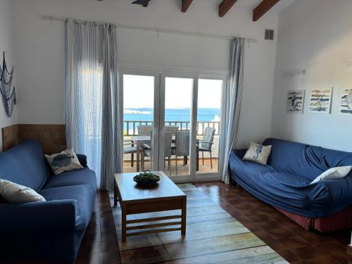 a living room with blue couches and a table at House with sea views and pool in Arenal del Castell in Arenal d'en Castell
