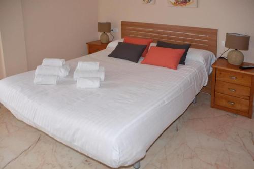 a large white bed with red and black pillows at CASA PATIO LAS PALMERAs 3 y 4 in Córdoba