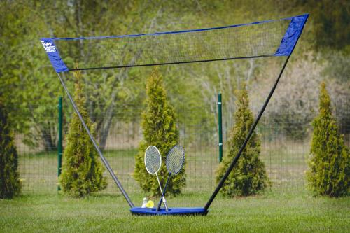a net with two tennis rackets on the grass at Atpūtas mājiņas Kolkā- Madaras un Rota in Kolka