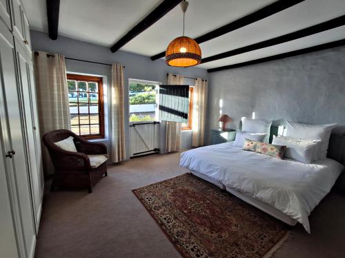 a bedroom with a large white bed and a chair at Schalkenbosch Heritage Cottages in Tulbagh