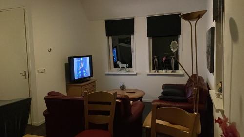a living room with a table and a television at Nieuw gebouwd appartement op paarden bedrijf in Buitenpost