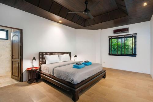 a bedroom with a bed with blue pillows on it at The Sunhouse at Paradise Village in Ban Bang Po