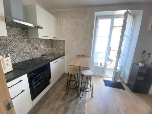 une cuisine avec des armoires blanches et un plancher en bois dans l'établissement Studio cosy, à Besançon