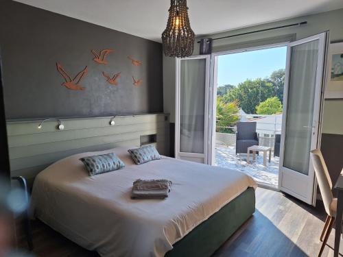 ein Schlafzimmer mit einem Bett und einem großen Fenster in der Unterkunft Atlantic Hôtel in Saint-Pierre-dʼOléron