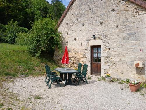 a table with chairs and a red umbrella in front of a building at Maison vacances 4 personnes in Mont-Saint-Jean