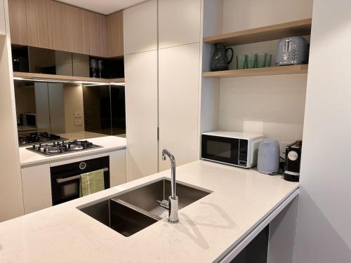 una cocina con fregadero y microondas en Queens Wharf TWO Bedrooms Apt, en Brisbane