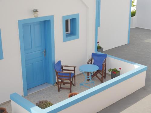 a house with a blue door and chairs and a table at Ancient Thera Apartments in Kamari