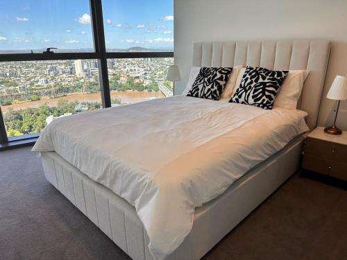 a large white bed in a room with a large window at LVL43 Queens Wharf 1BR Apartment in Brisbane
