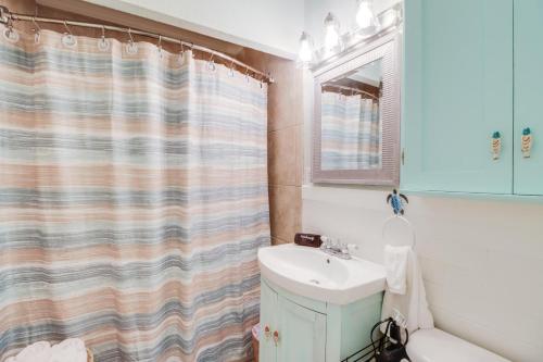 a bathroom with a sink and a shower curtain at The Little Sandy Flamingo in Gulfport