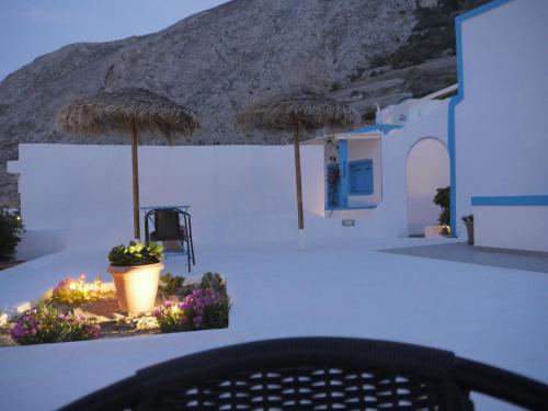 a table with two umbrellas and a chair and flowers at Ancient Thera Apartments in Kamari