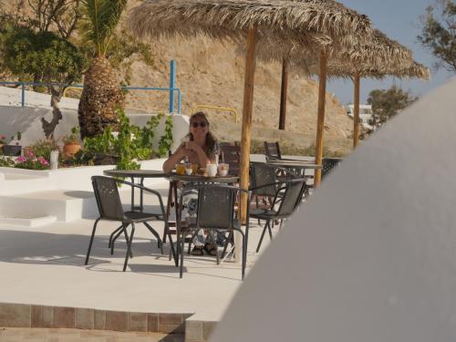a woman sitting at a table on a patio at Ancient Thera Apartments in Kamari